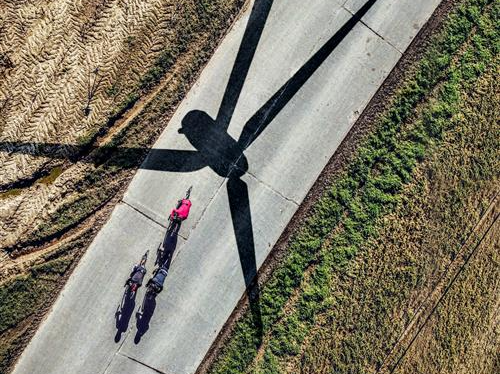 Een fietser rijdt in de schaduw van een windmolen